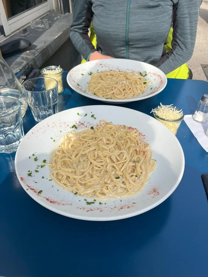 Deux assiettes de pâtes en sauce crémeuse sur une table bleue